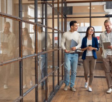 three colleagues walking in hallway of modern offic