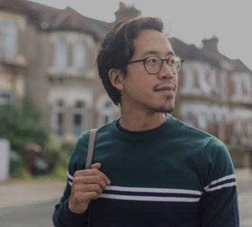 pensive male college student walking in residential area
