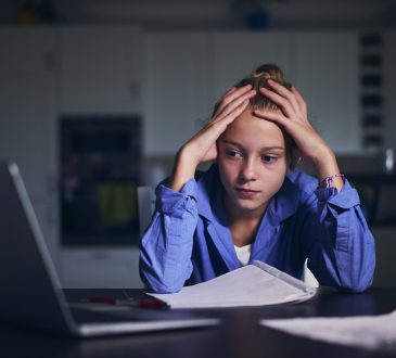Schoolgirl learning via internet with laptop at home.