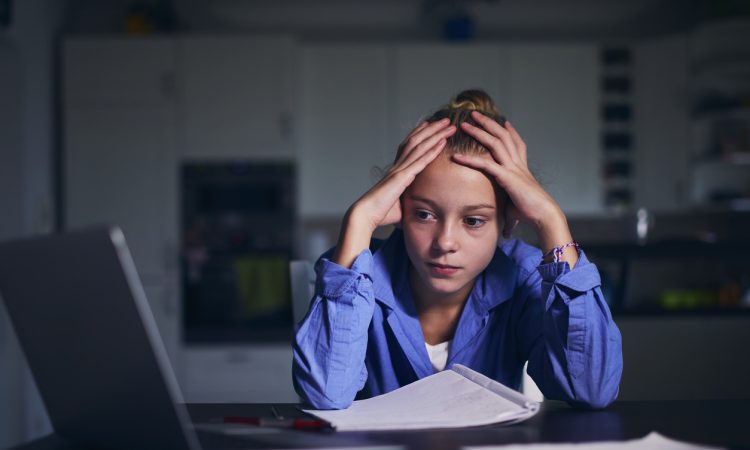 Schoolgirl learning via internet with laptop at home.
