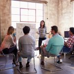 Group of people watching woman present in office