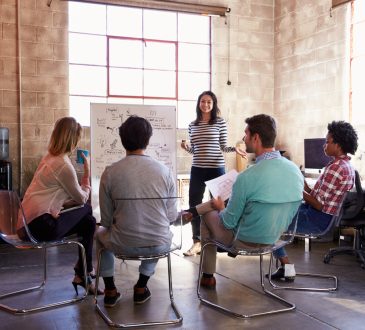Group of people watching woman present in office