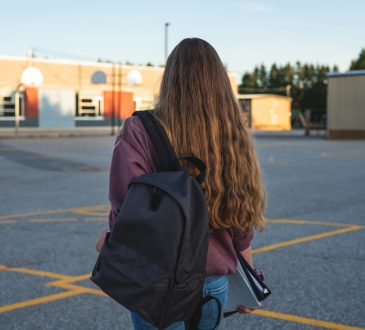 Teen girl walking through school's outdoor basketball court.