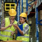 Man and woman discussing inventory in warehouse.