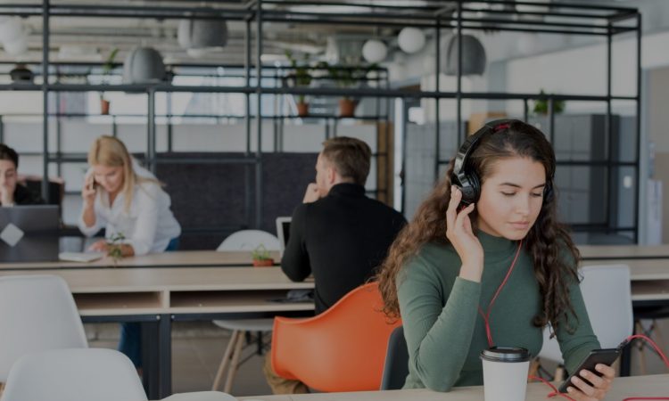 Young woman wearing headphones in open-concept office.