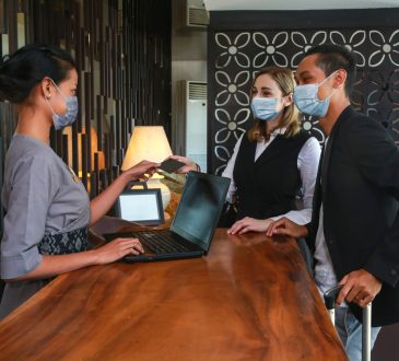 Couple and receptionist at counter in hotel.