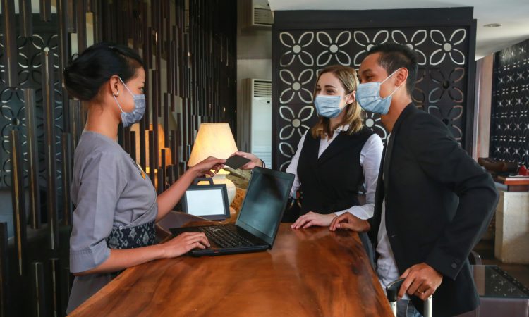 Couple and receptionist at counter in hotel.