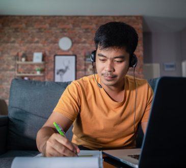 Man writing in notebook while working from home.