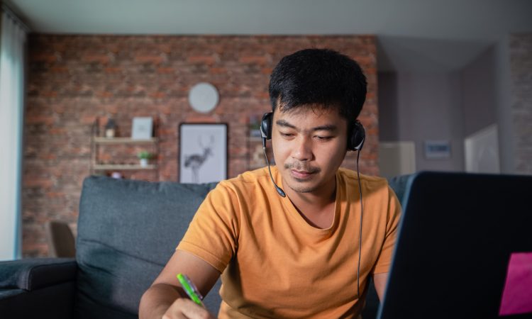 Man writing in notebook while working from home.