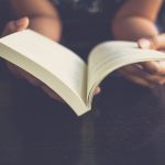 Close up of hands holding open book.