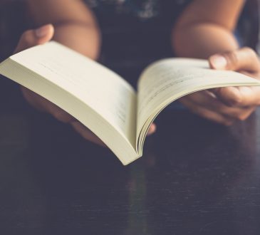 Close up of hands holding open book.