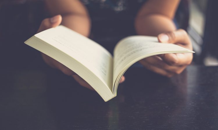 Close up of hands holding open book.
