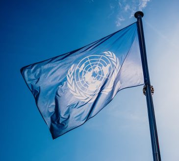 UN flag against blue sky.