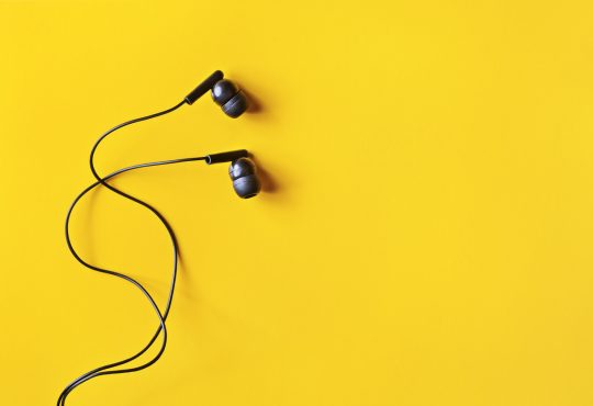 Black ear buds on yellow background