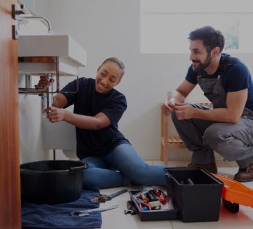 Apprentice and plumber fixing sink