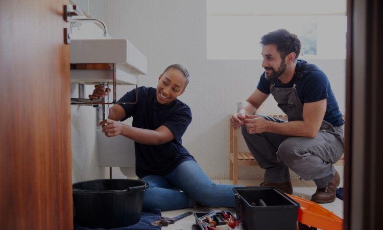 Apprentice and plumber fixing sink
