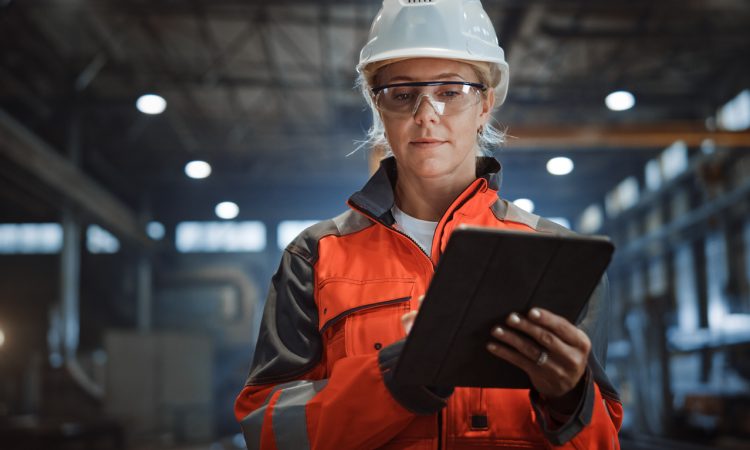 Female Industrial Specialist Walking in a Metal Manufacture Warehouse.