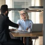 Smiling mature businesswoman shaking hand of young businessman