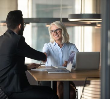 Smiling mature businesswoman shaking hand of young businessman