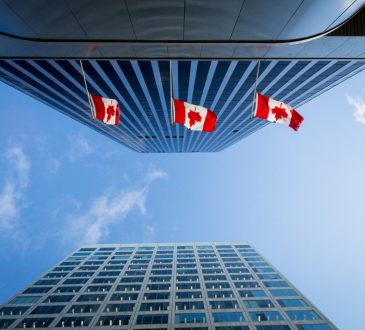 Canadian flags on skyscraper buildings seen from underneath