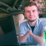 Young man with no hands sitting at laptop in cafe