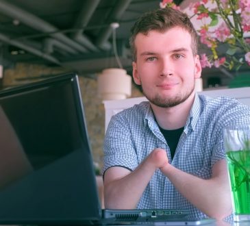 Young man with no hands sitting at laptop in cafe