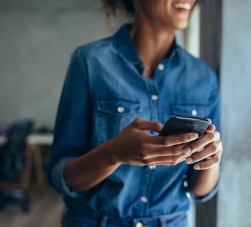 Woman standing by window texting.