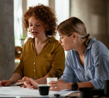 Two women looking at papers on desk together