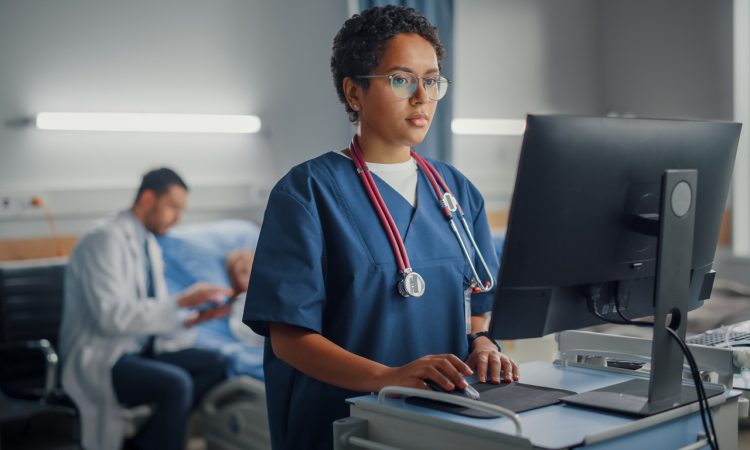Black doctor using computer in hospital