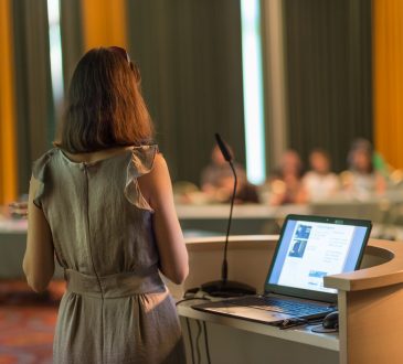 Woman speaking to room of people at podium