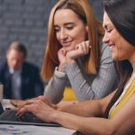 Two women looking at laptop screen together at work