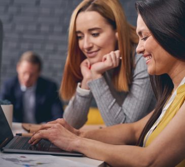 Two women looking at laptop screen together at work