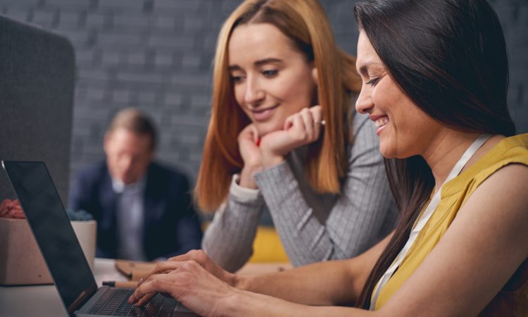 Two women looking at laptop screen together at work