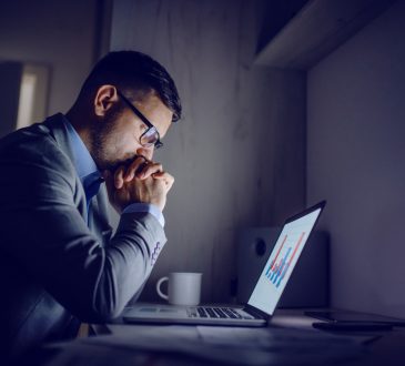 Stressed man working on laptop at night