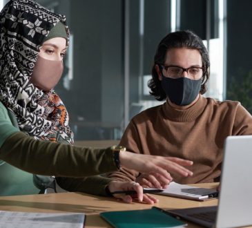 Man and woman wearing masks and looking at computer