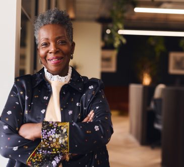 Portrait of confident senior black woman smiling and looking at camera with arms folded