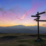 Wooden signpost on mountain at sunset