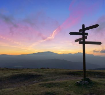 Wooden signpost on mountain at sunset