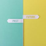 Wood stick with small white flags on yellow and blue background showing past and future