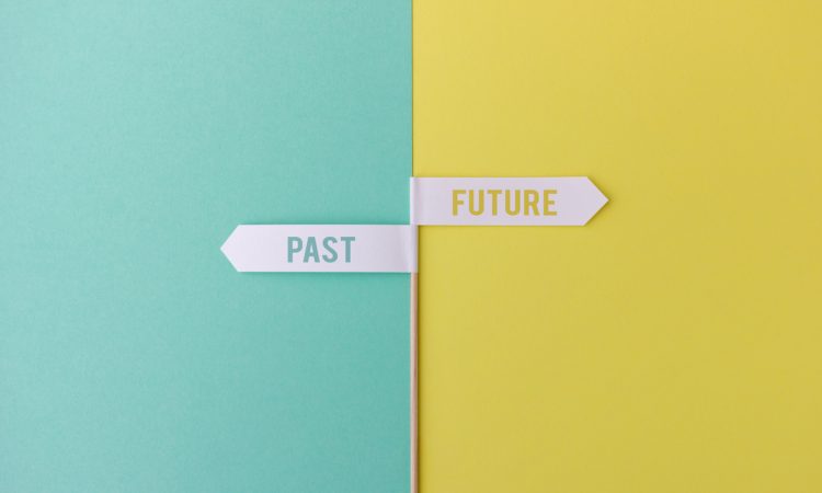 Wood stick with small white flags on yellow and blue background showing past and future