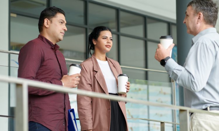 Coworkers talking during coffee break outside of building