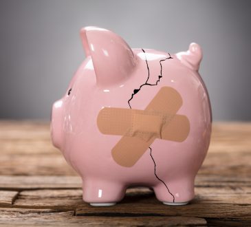 Closeup of broken pink piggybank with bandage