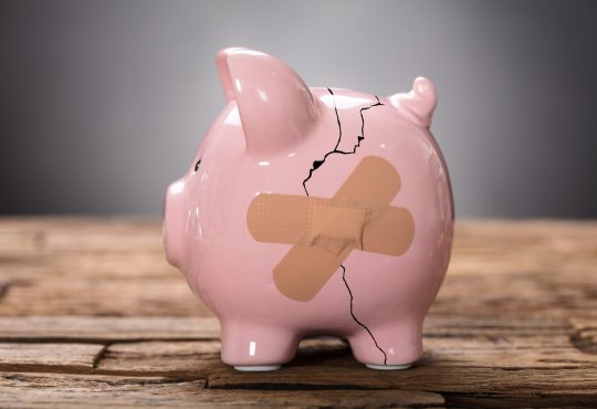 Closeup of broken pink piggybank with bandage