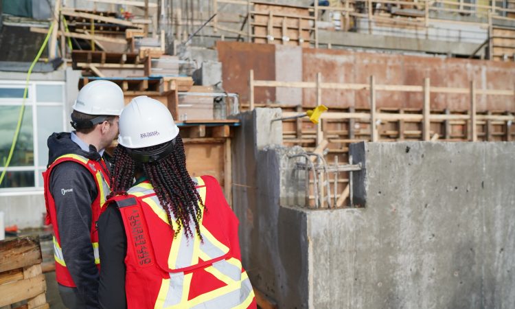 Two people looking at foundation on construction site