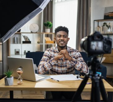 Man sitting at desk in home office recording video on camera