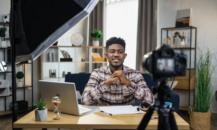 Man sitting at desk in home office recording video on camera