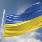Ukrainian flag against blue sky with clouds