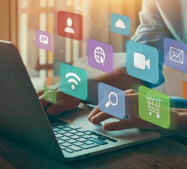Person typing on laptop with overlay of colourful icons representing internet, online shopping, video, etc.