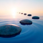 Dark stones in calm water with evening sun