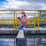 Worker take water from the wastewater treatment pond to check the quality of the water.